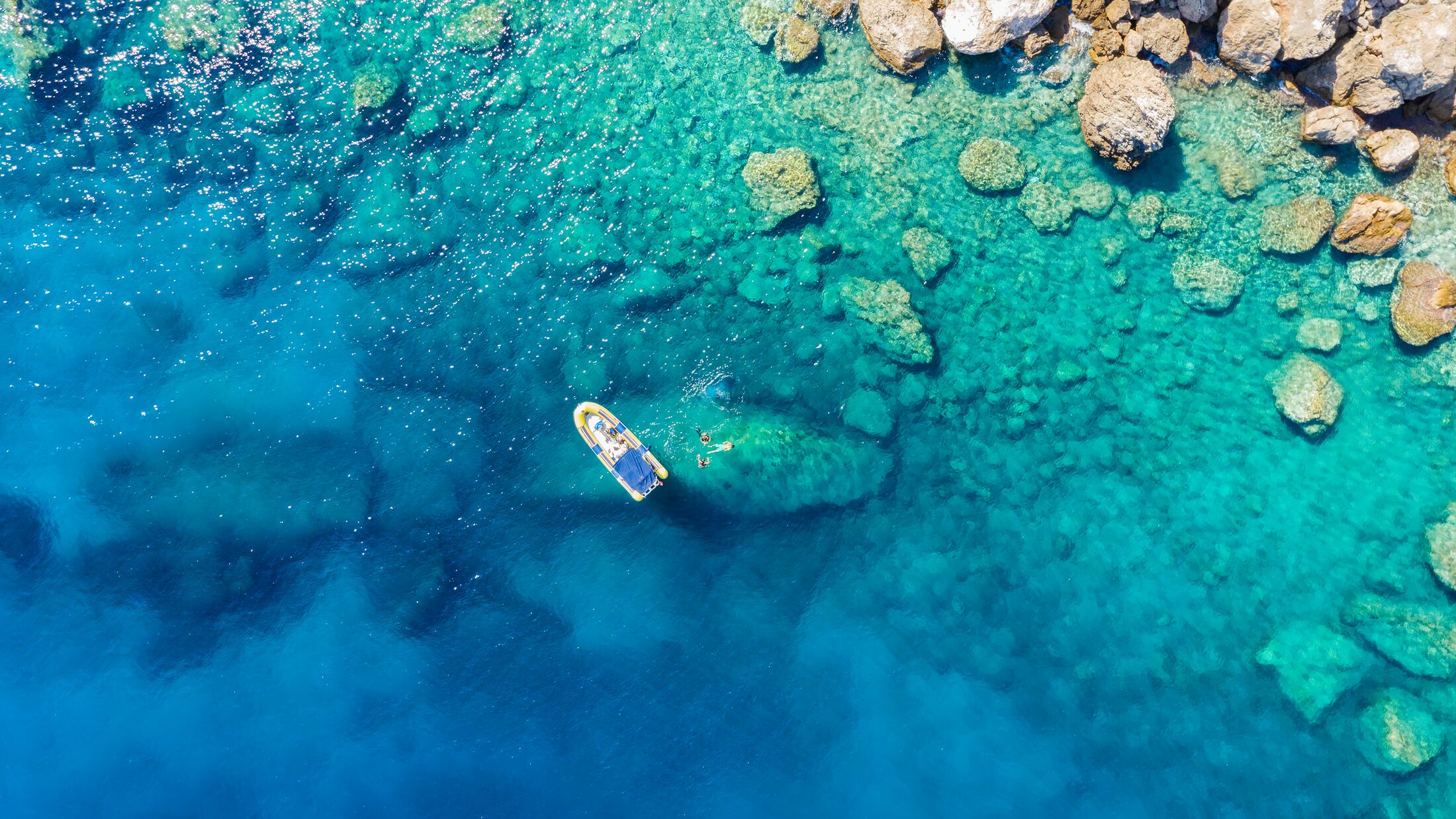 Aerial view of a rib boat with snorkelers and divers at the turquoise colored coast of the Aegean Sea in Greece