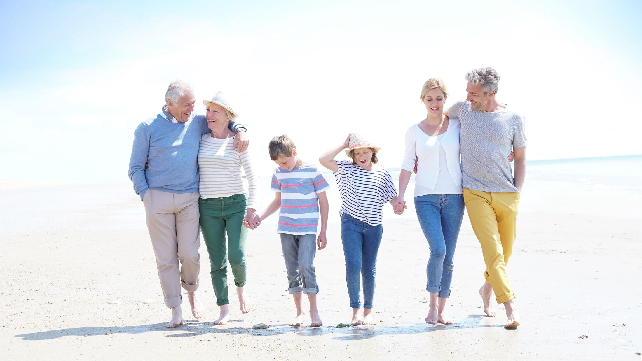 Family, parents, grandparents and grandkids walking on the beach