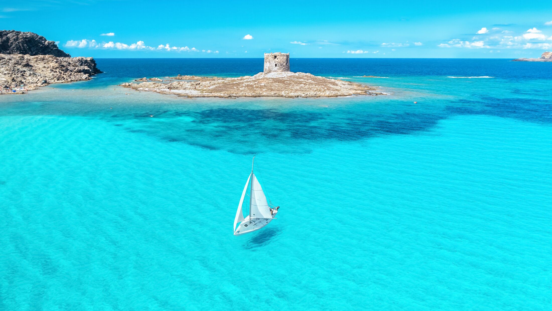 Beautiful seascape with white sailing yacht in summer on a sunny day aerial view. Popular beach La Pelosa, Sardinia, Italy. Travel, hobby concept